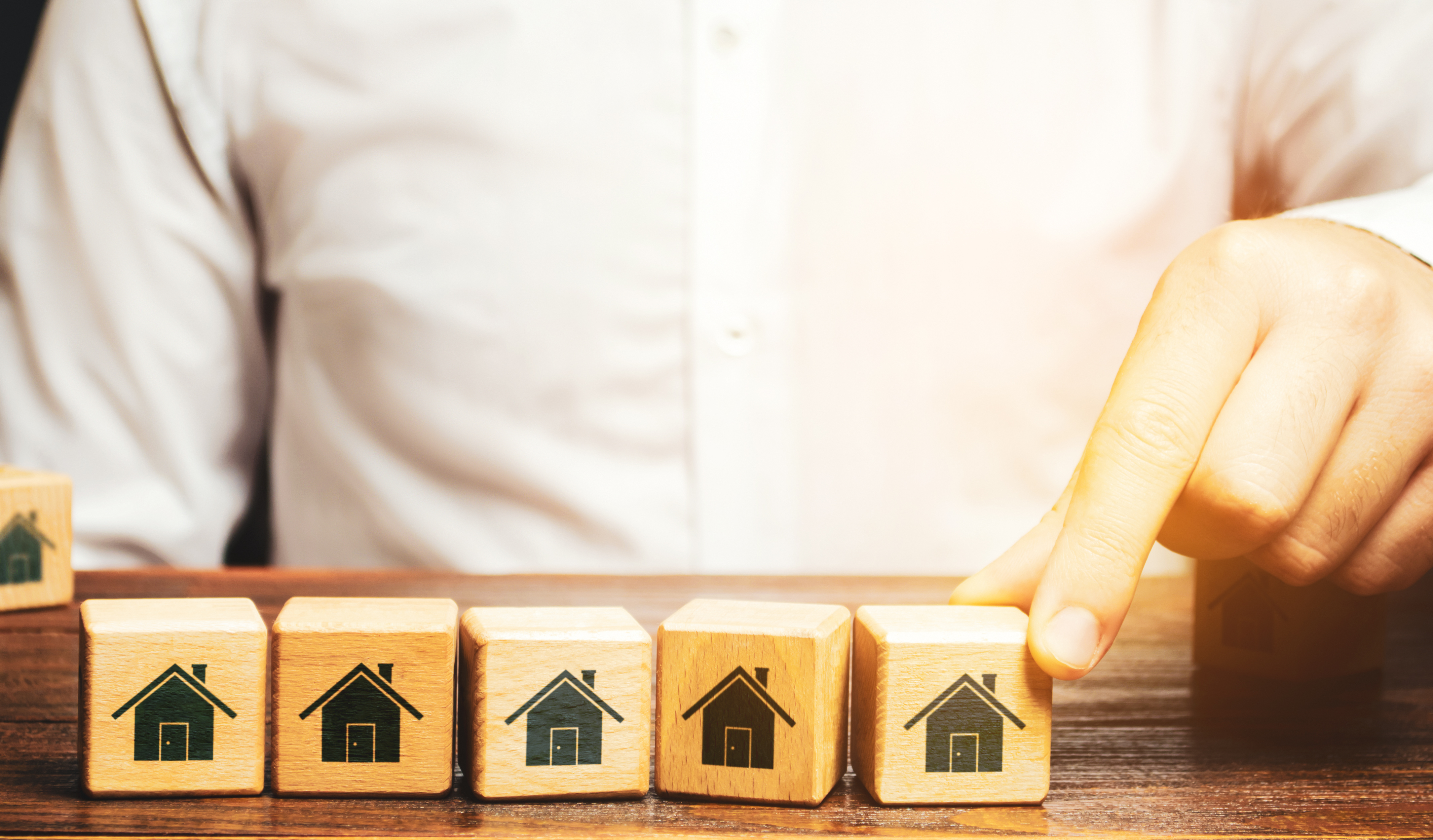 Person arranges wooden blocks with houses painted on them